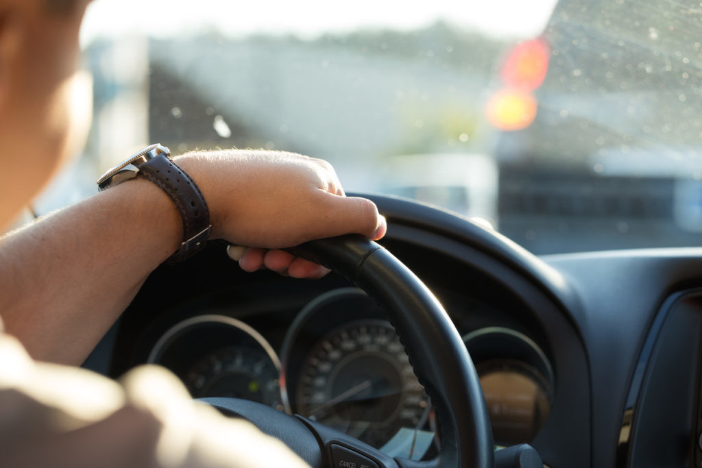 Man behind the wheel in the evening. Young man goes in the car to home after work.