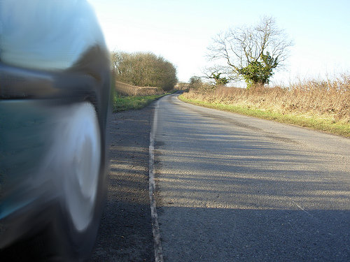 Primer plano de la rueda de un coche que circula cerca de una línea longitudinal continua. Fotomontaje