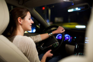 Driving a car at night - pretty, young woman driving her modern