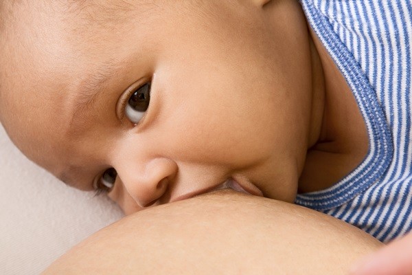 ethnic Infant of mixed ethnicity (Hispanic and African-American) sucking milk form his mother breast while she is nursing him