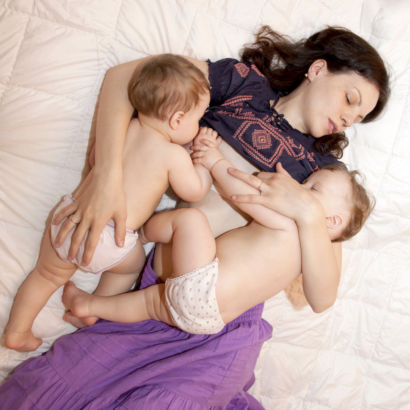 Breast feeding two little sisters twin baby girls at the same time. Mother's love