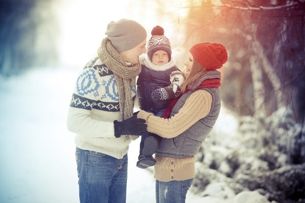 Happy young family portrait on winter surrounded by snow.