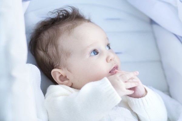 Beautiful little baby relaxing in a stroller wearing a warm white sweater