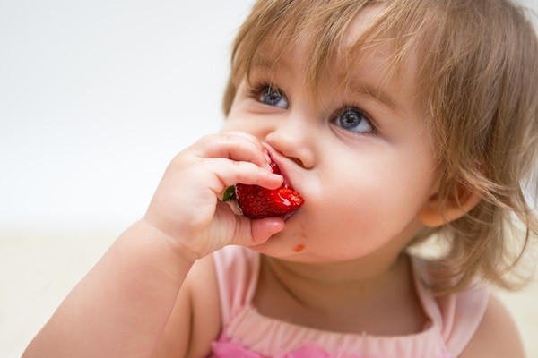 Portrait of a beautiful little girl with strawberry