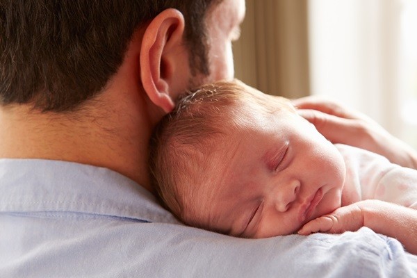 Father At Home Holding Sleeping Newborn Baby Daughter