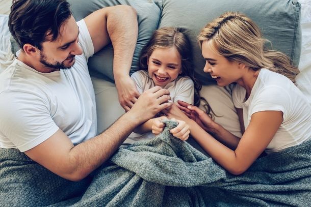 Una pareja y su hija sonrientes en la cama