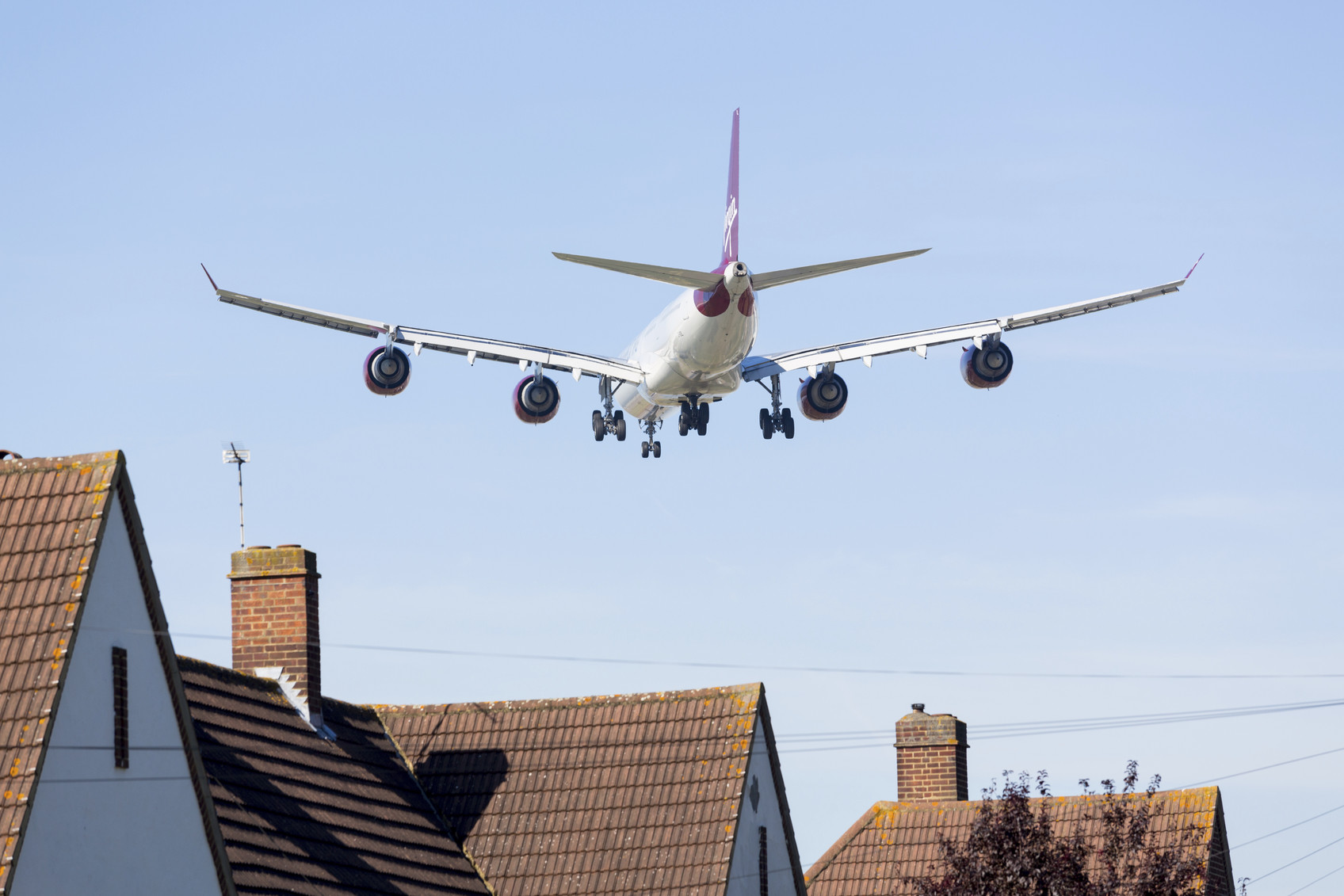 Heathrow Airport, London, England - September 9, 2012: Virgin Atlantic Airbus A340 approaches Heathrow Airport flying low over homes near the runway