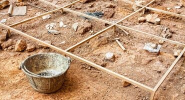 excavación arqueológica con líneas para marcar zonas y útiles como martillo, pincel o cubo